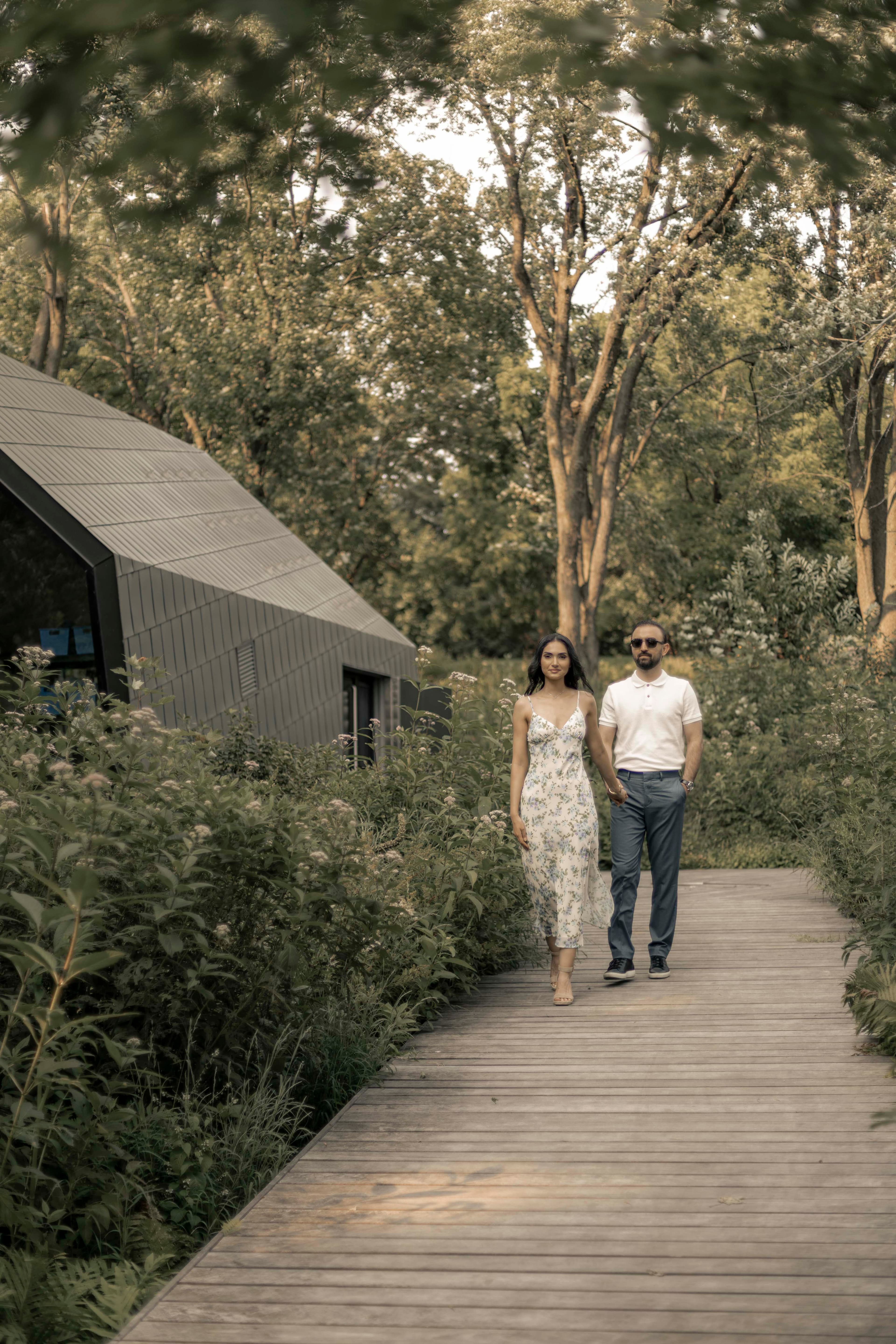 A couple walking a tree-lined boardwalk at golden hour