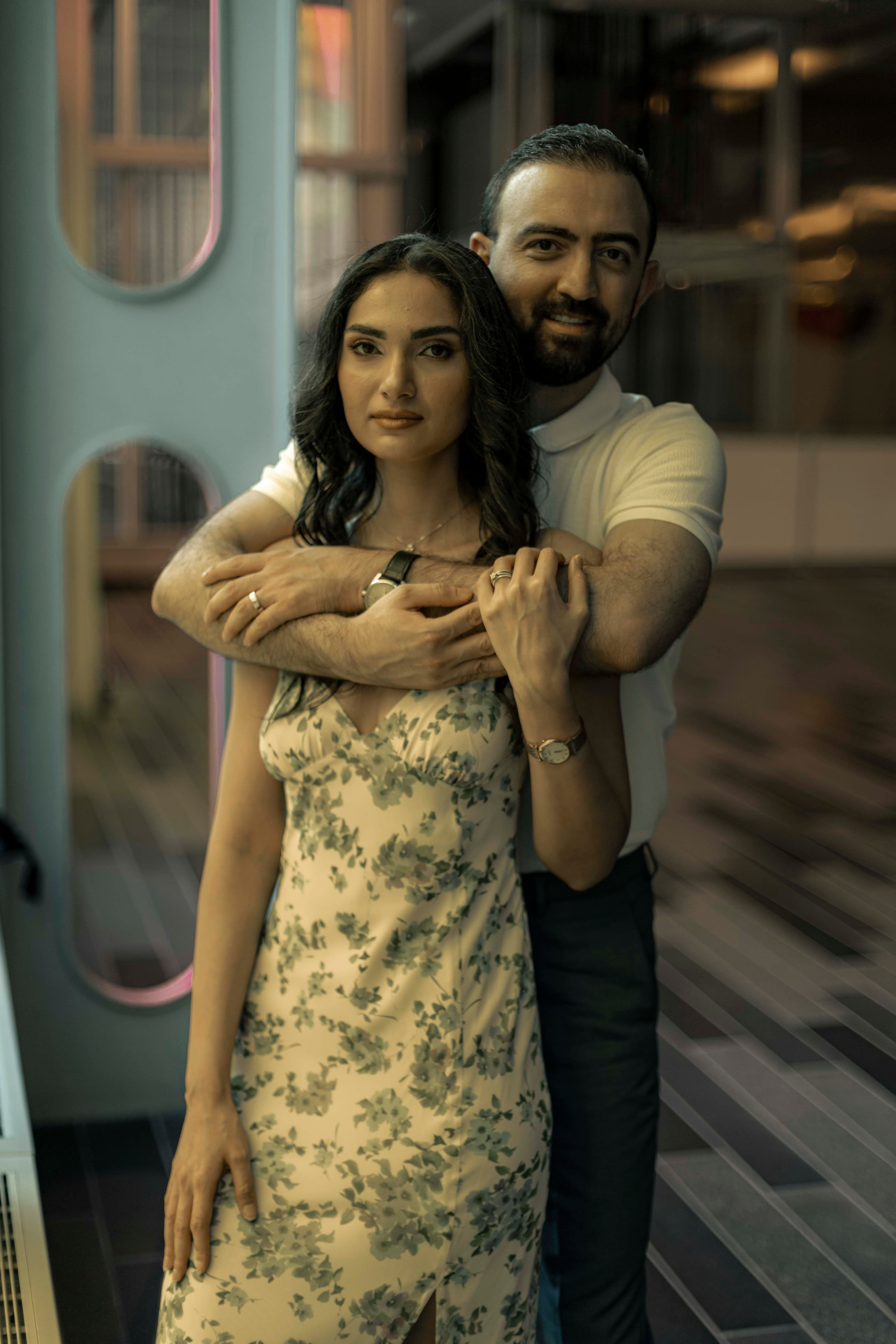 A couple standing close together against a turquoise wall