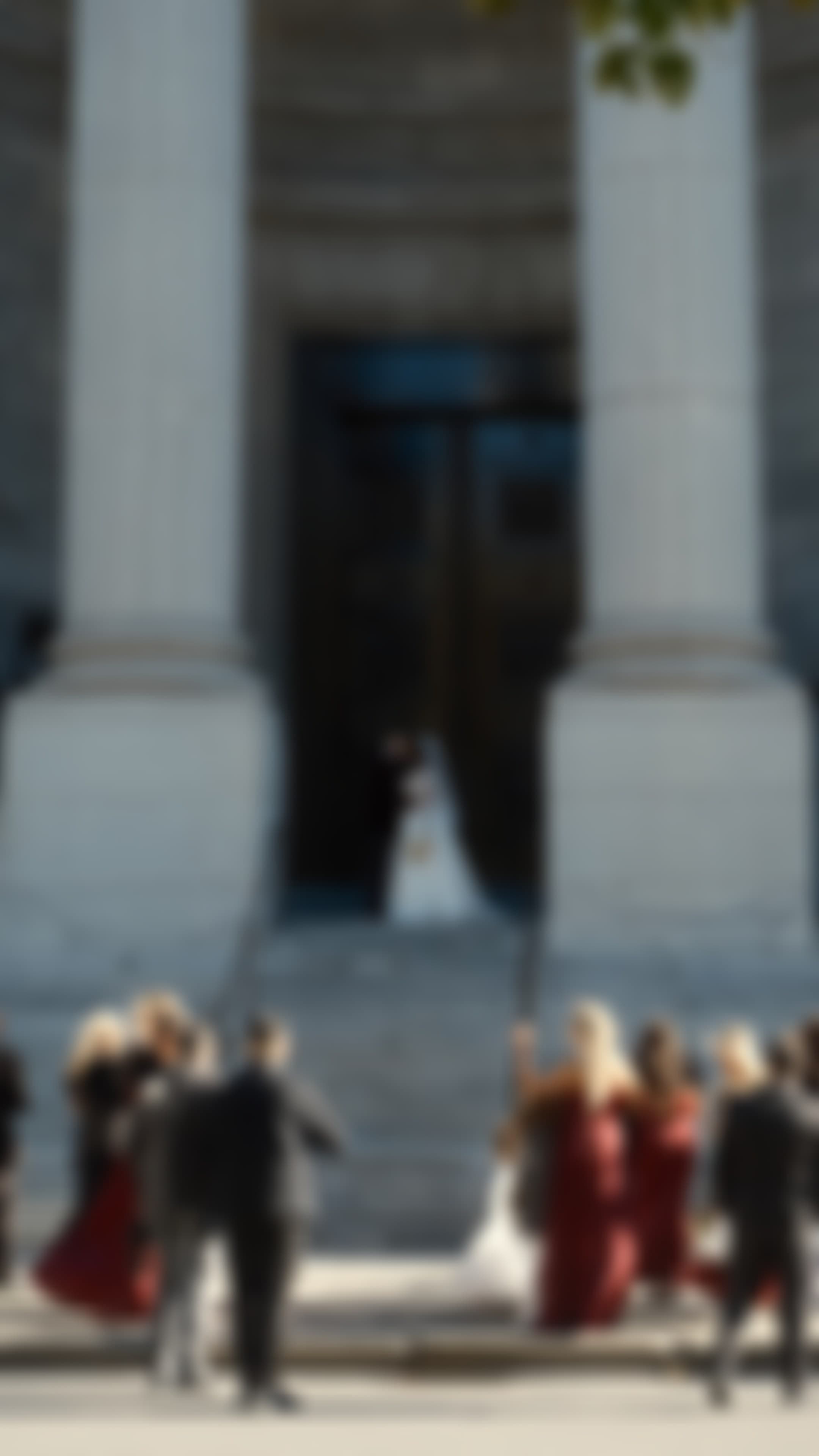 A softly blurred photograph of a couple in the doorway of a columned building